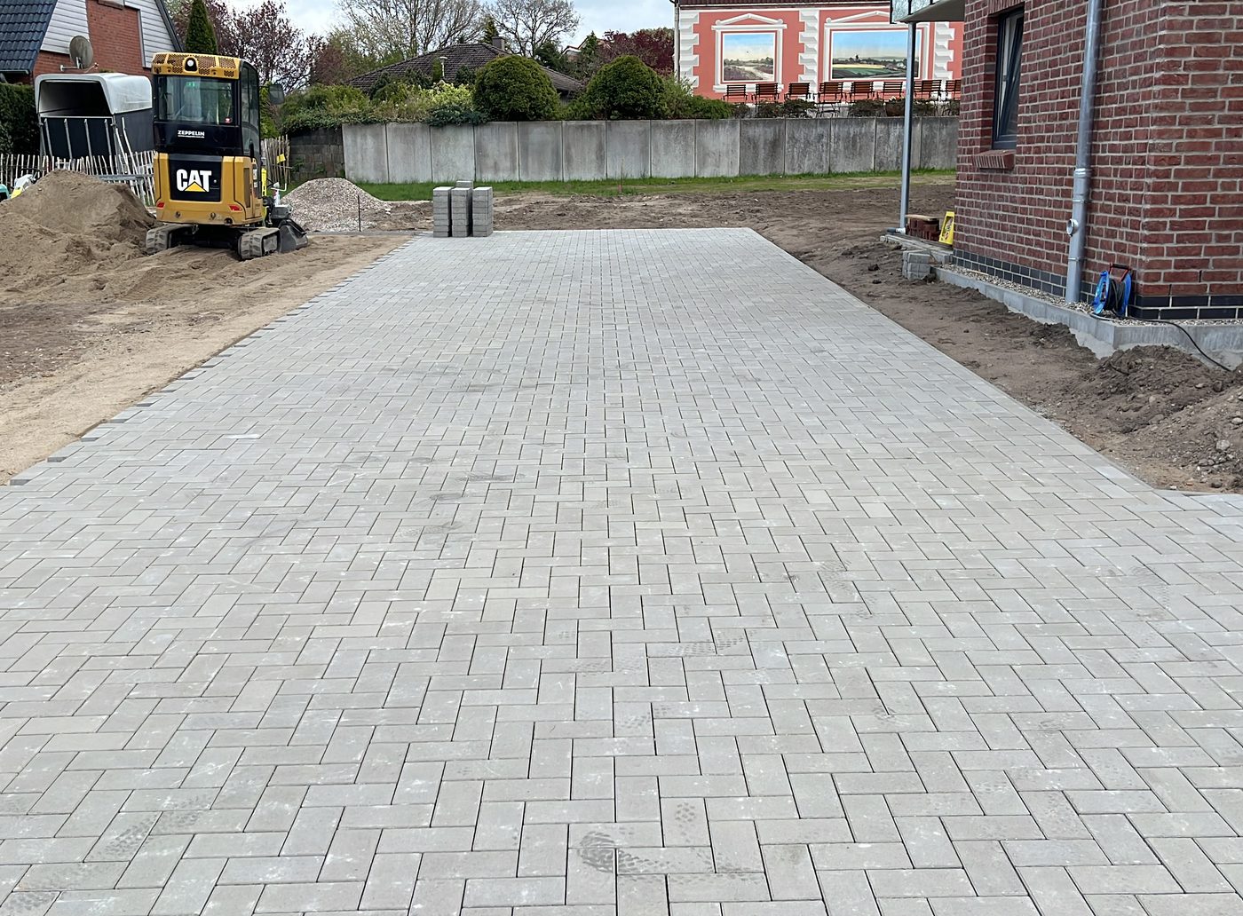 Fertig gepflasterte Einfahrt aus Betonsteinen vor einem Klinkerhaus