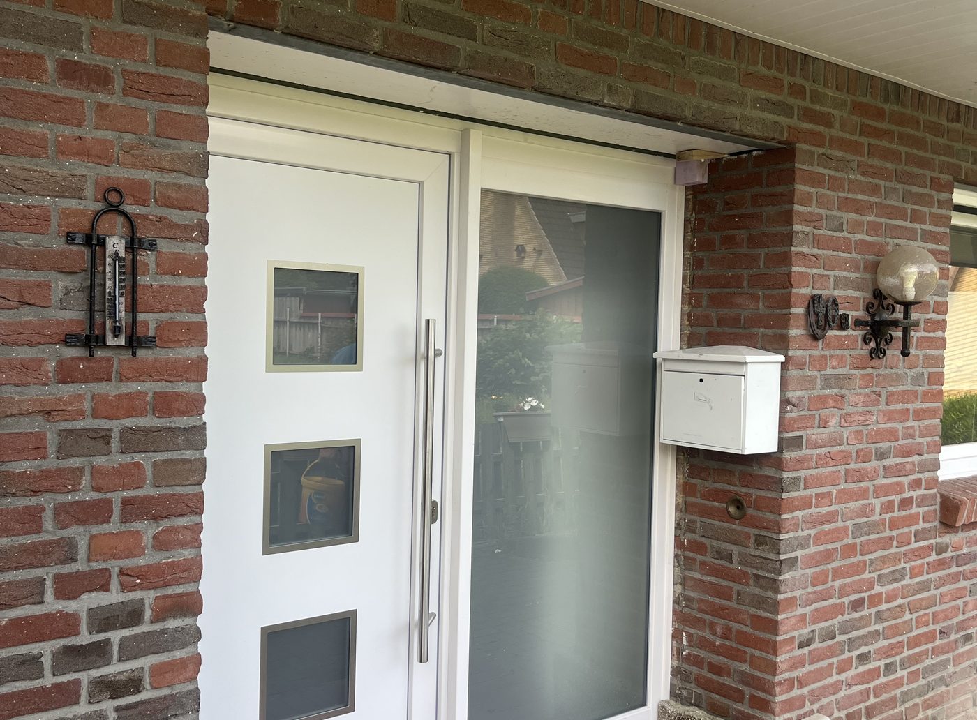 Neu eingebaute weiße Haustür in einer Klinkerfassade