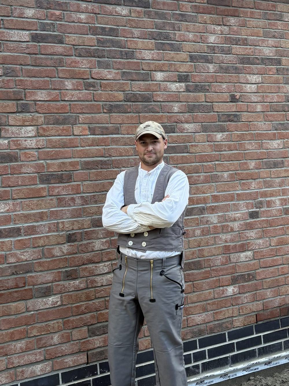 Max Bockmann, Maurermeister, in Zunftkleidung vor einer Klinkerfassade