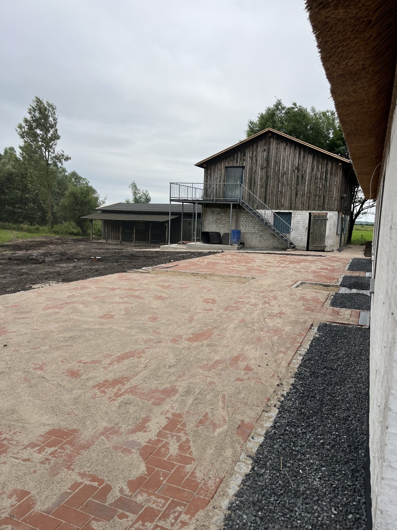 Neu gepflasterter Hof vor einem Reetdachhaus, Schotterstreifen als Randeinfassung